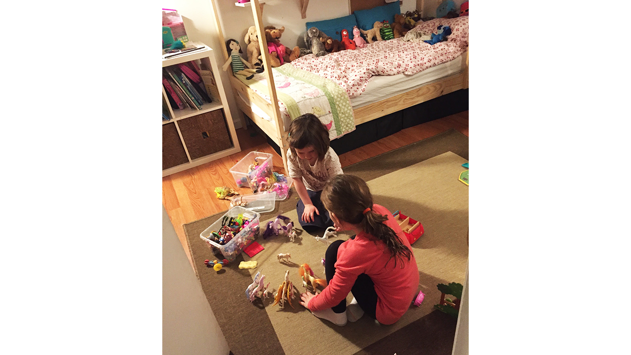 two young kids playing with toys on the floor of their bedroom