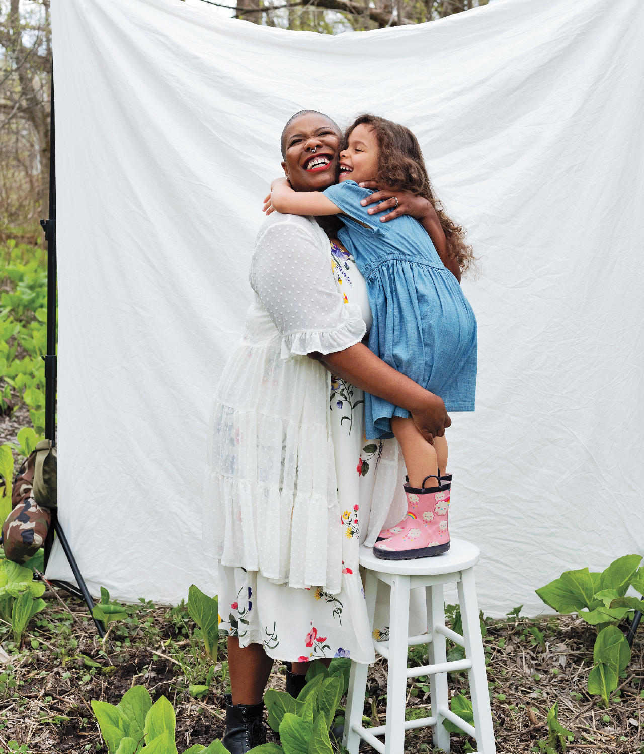 a mother hugs her preschooler, who is standing on a stool