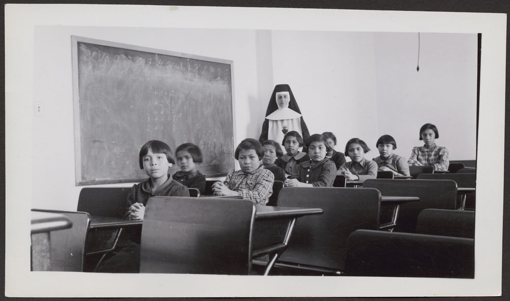 a photo of young female indigenous students in a residential school classroom in 1940