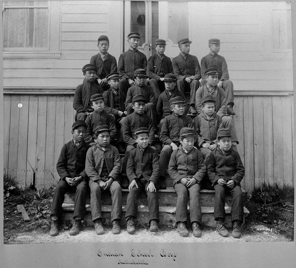 nineteen indigenous students wearing uniforms seated on a series of steps